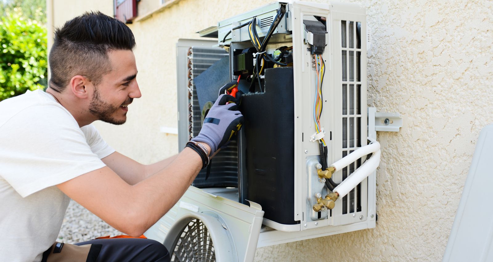 Gros plan sur l'intervention d'un technicien sur le bloc extérieur d'une climatisation durant l'installation.